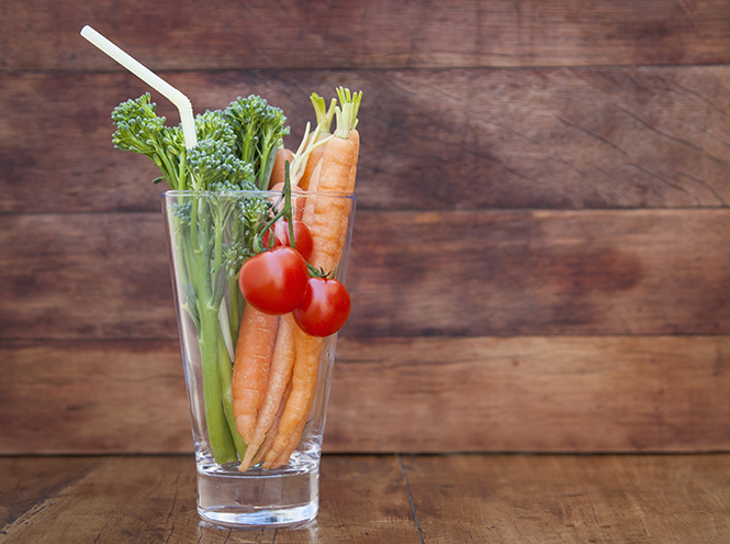 Glass of broccoli, carrots and tomato with straw
